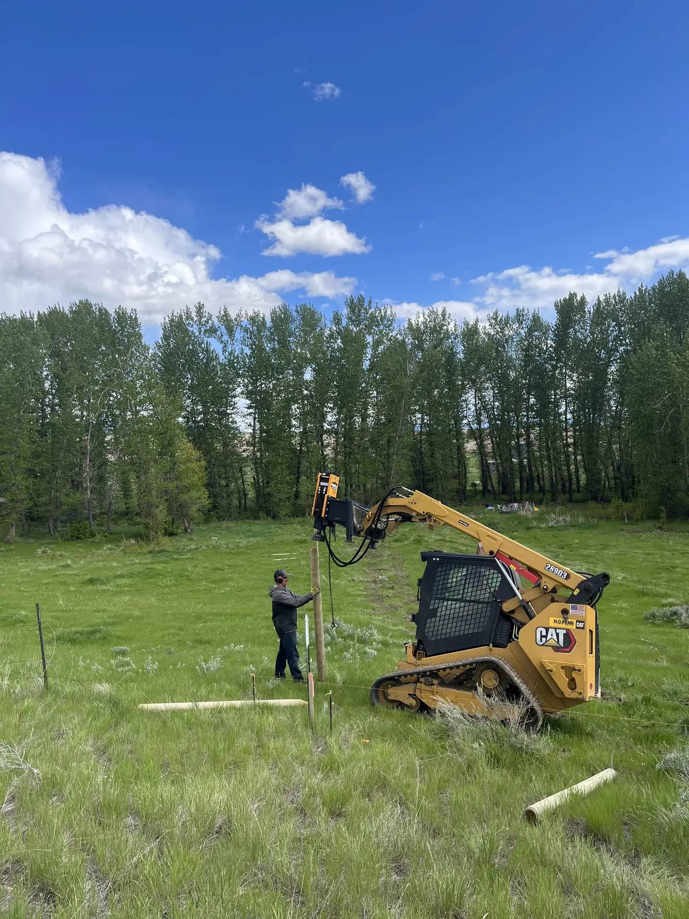 Driving a wood fence post with a skid-steer post pounder on a Belgrade-area pasture line
